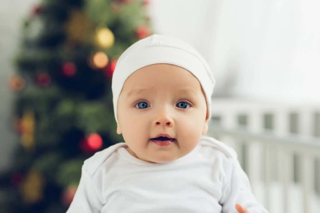 baby right next to Christmas tree