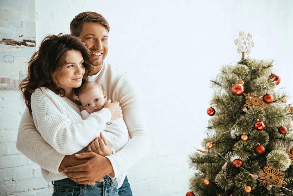 mom holding newborn by Christmas tree