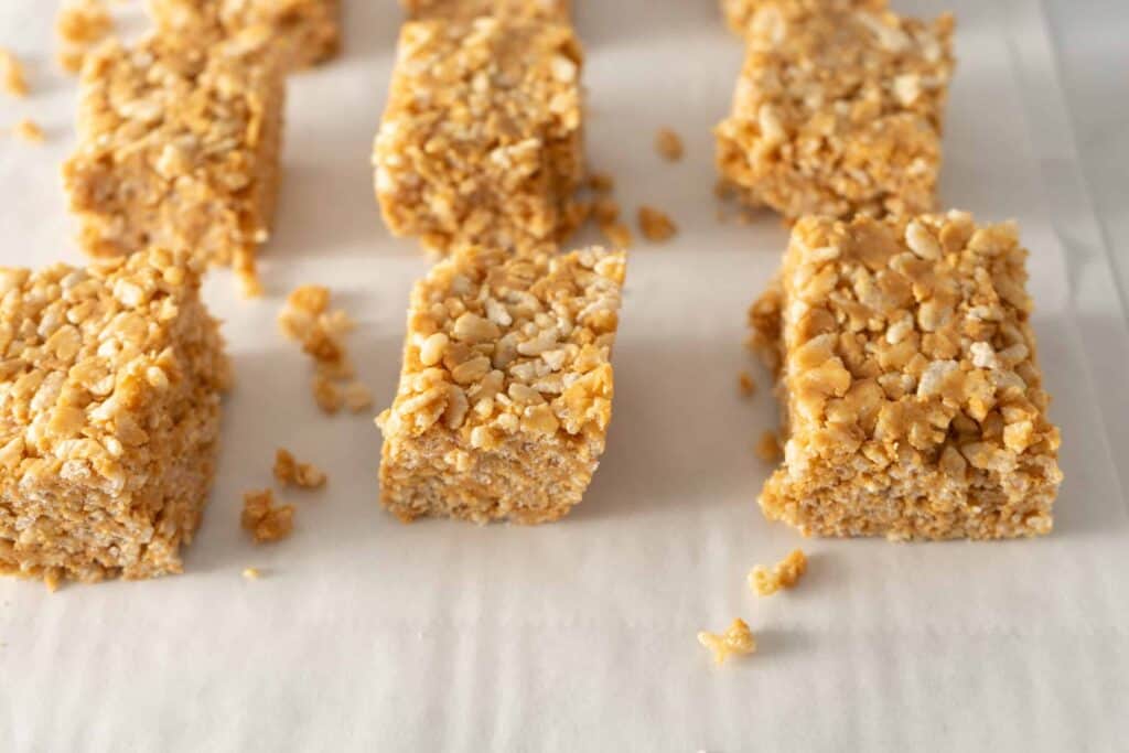 Neatly cut honey-peanut butter crispy bars arranged on parchment paper.