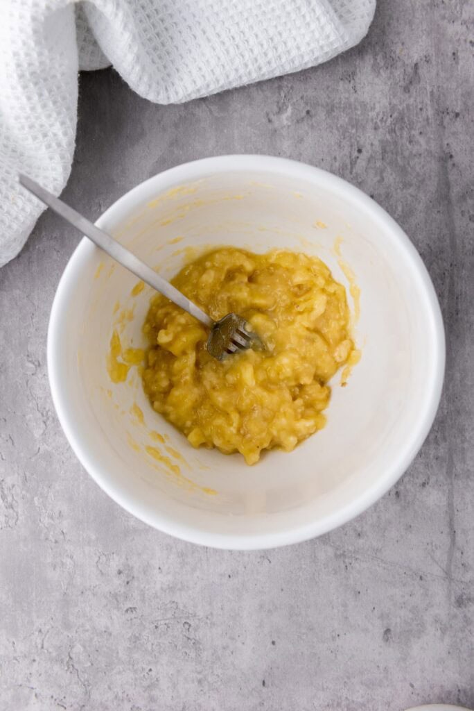mashed bananas in a white bowl with fork in it