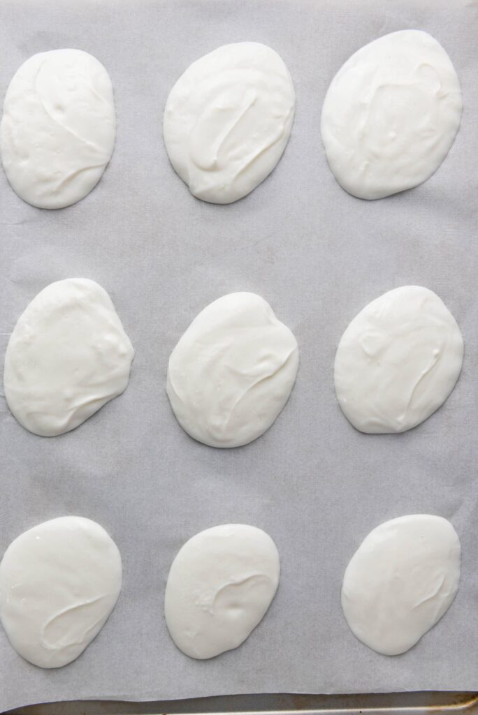 Bite-sized yogurt drops spread on parchment paper.