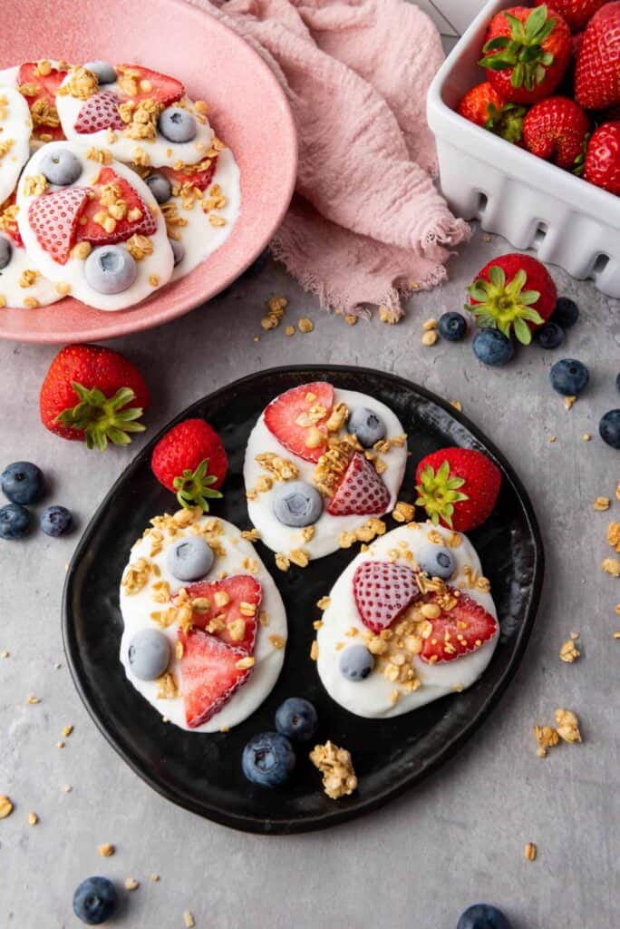 Delicious frozen vanilla yogurt bites topped with strawberries, blueberries, and crunchy granola. Pe.