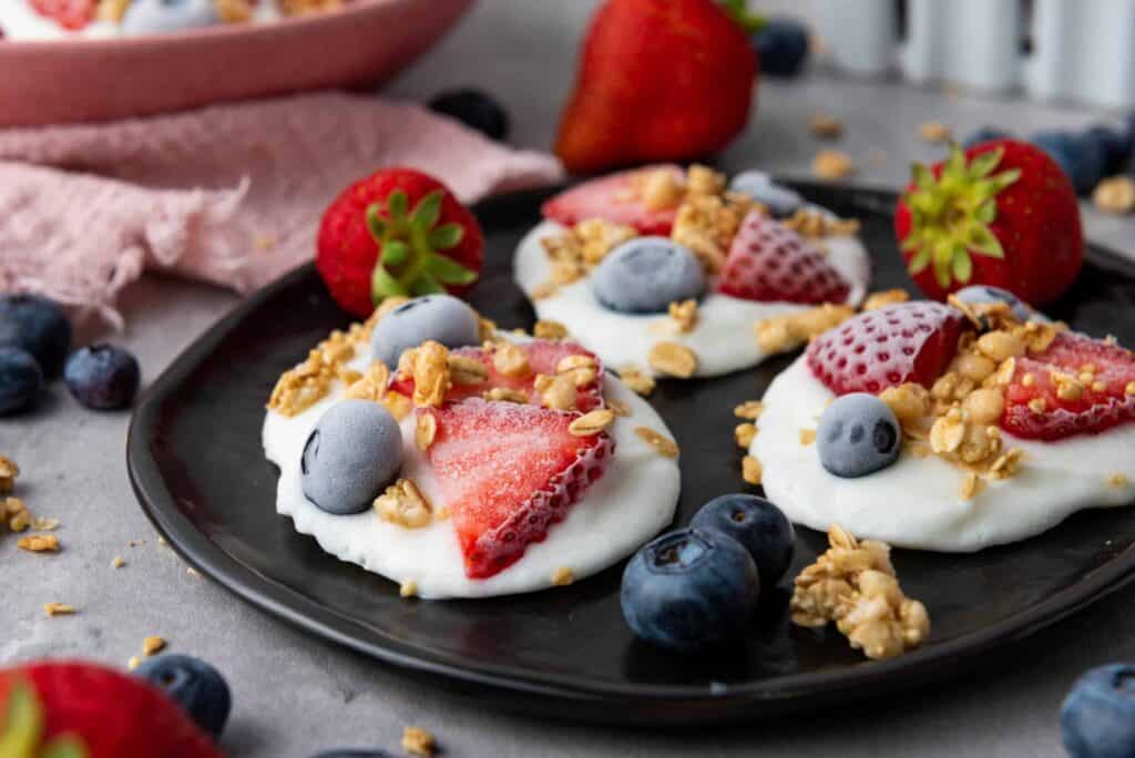 Frozen vanilla yogurt bites topped with fresh berries and crunchy granola for a refreshing, wholesome snack.