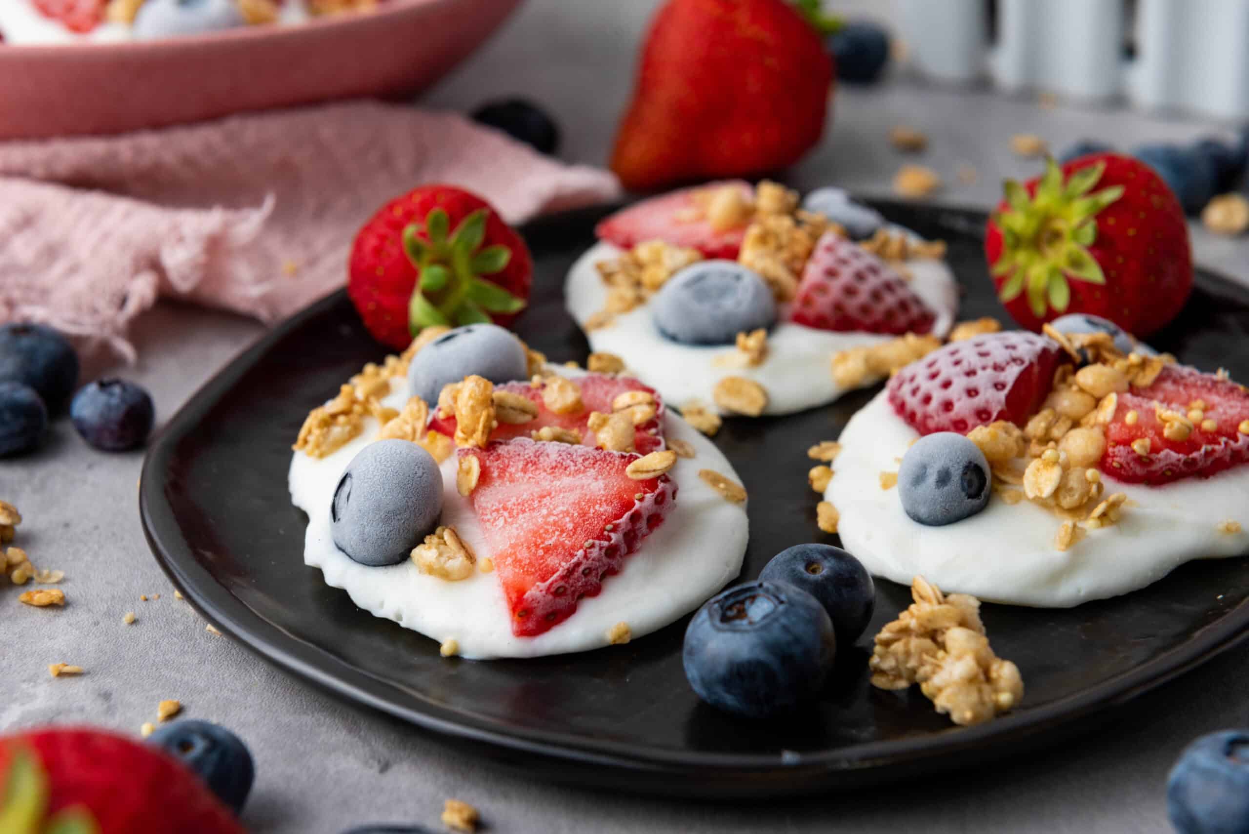 Frozen vanilla yogurt bites topped with fresh berries and crunchy granola for a refreshing, wholesome snack.
