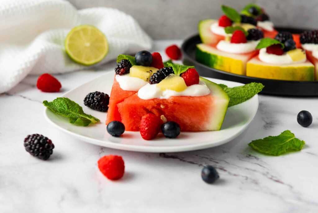 Colorful homemade watermelon pizza with fresh berries and mint leaves.