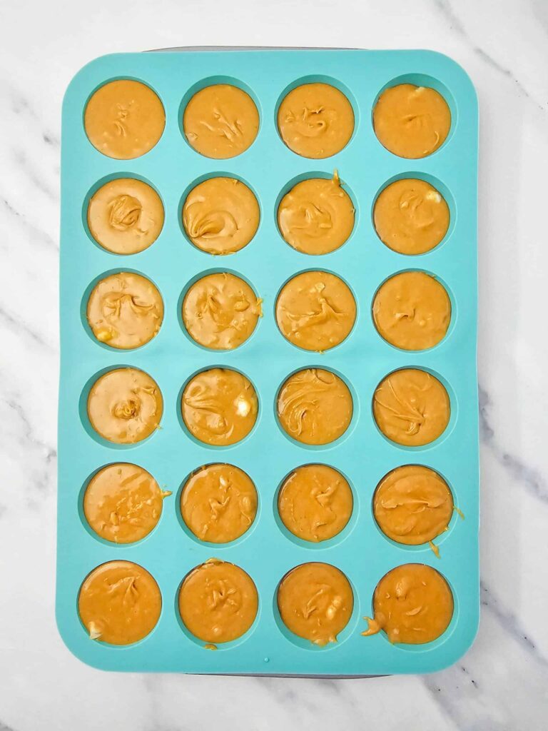 Peanut butter fudge mixture portioned evenly into a silicone mini muffin tray