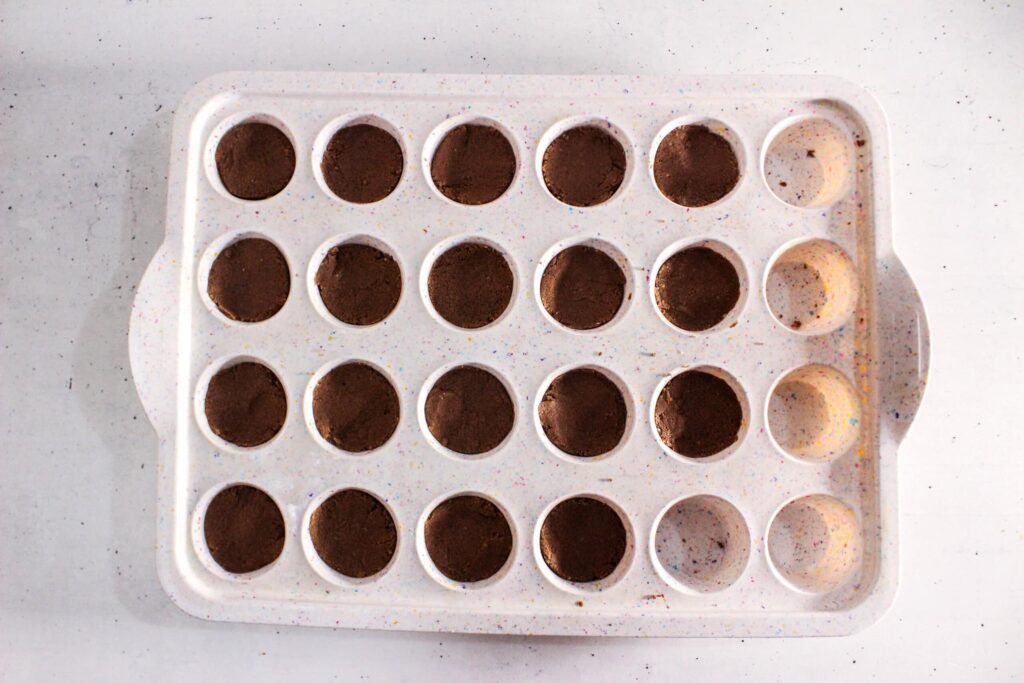 protein brownie batter pressed into a mini muffin silicone tray, ready to set.