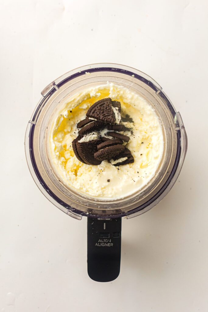 Adding Oreo biscuit pieces into the center of the ice cream mixture for mix-ins.