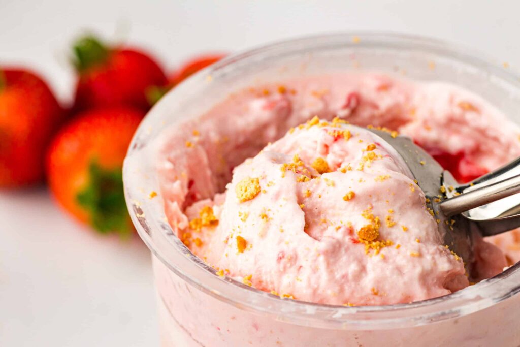 a scoop of strawberry ice cream topped with crushed biscuits.