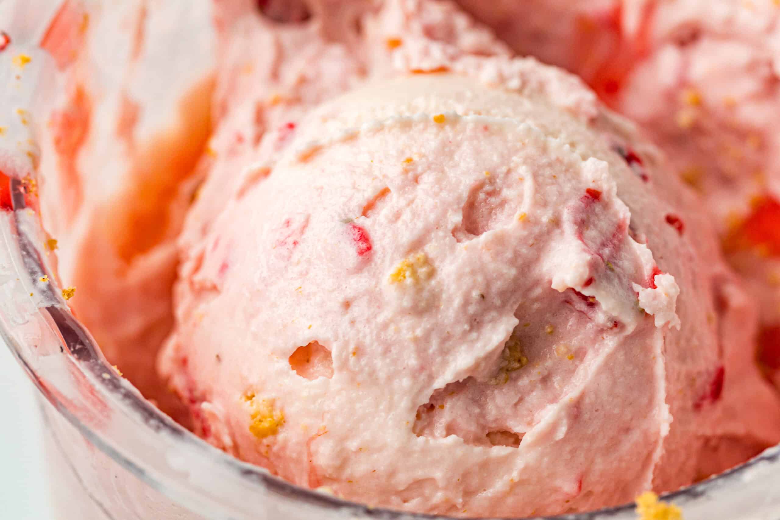 Strawberry ice cream served in a bowl with juicy strawberry bits and a crumbly topping.