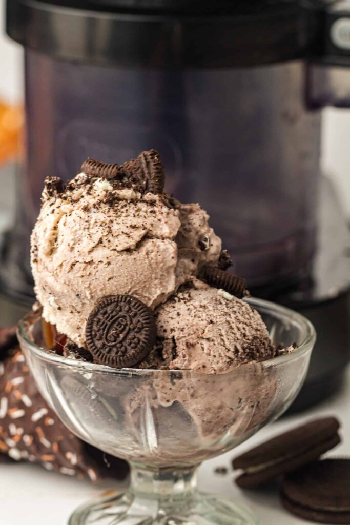 Delicious cookies and cream ice cream served in a glass bowl, topped with crushed cookies and whole.